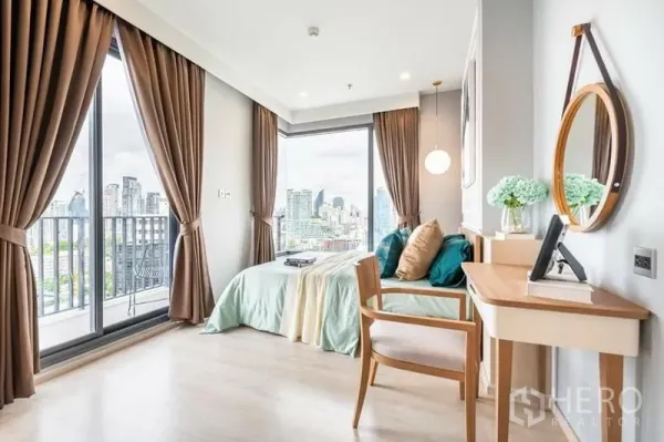 Condominium for rent or sale in Watthana, Bangkok - Bedroom with floor-to-ceiling windows, vanity desk and panoramic Bangkok skyline view.