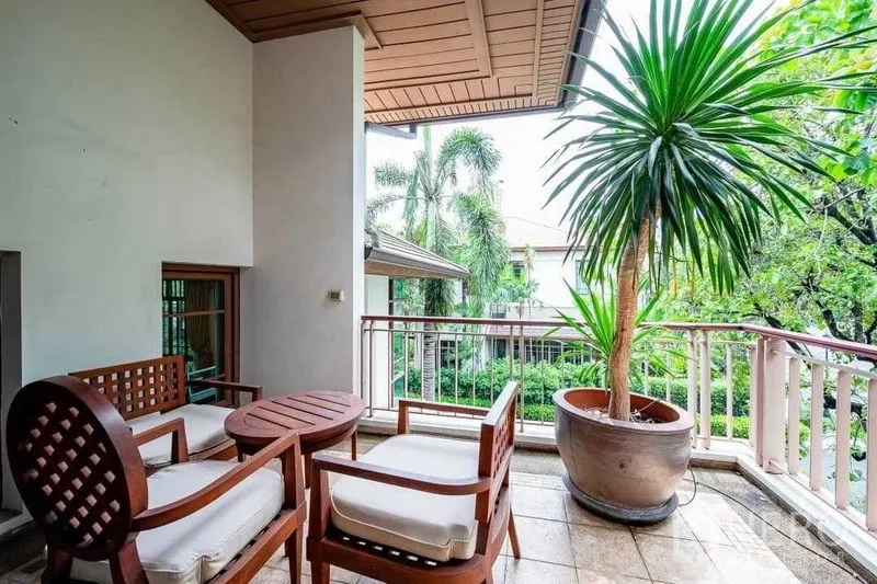 Detached House for sale - Covered balcony with seating set and potted palm overlooking greenery.