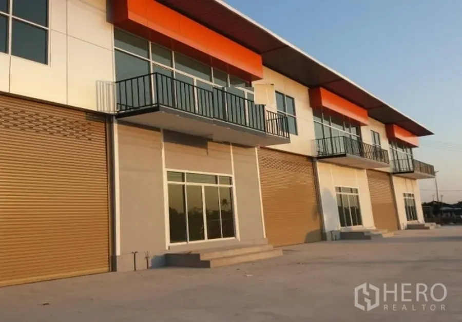 工厂 出租在Pathum Thani - 现代工厂立面，带阳台、玻璃入口与多樘卷帘门。