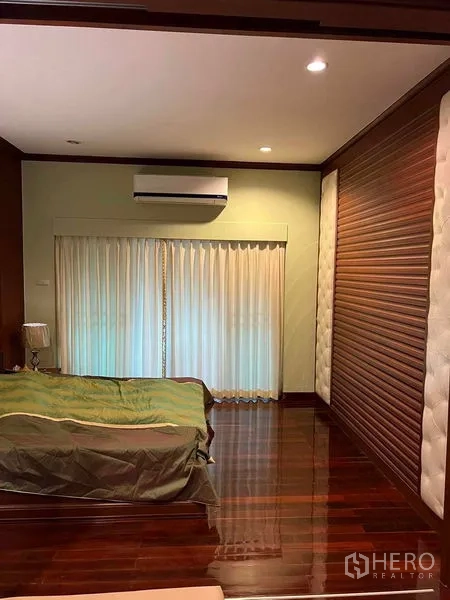 Detached House for sale in Bueng Kum, Bangkok - Large bedroom with wood floors, air conditioning, and full-height curtains.