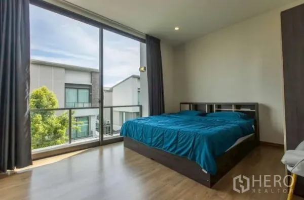 独立式住宅 出租或出售在Lat Phrao, Bangkok - 采光充足的卧室，落地窗连接阳台，眺望社区景观。