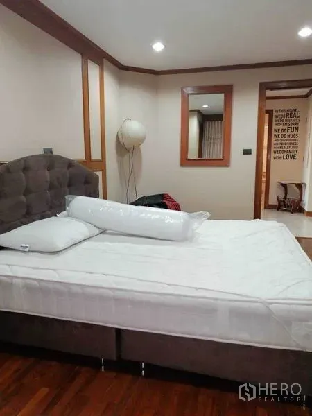 Condominium for rent in Watthana, Bangkok - Cozy bedroom with upholstered headboard, wood floors and soft lighting.