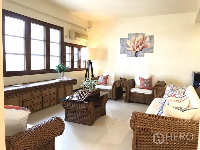 บ้าน ให้เช่าในPhra Khanong, Bangkok - ห้องนั่งเล่นโปร่ง เฟอร์นิเจอร์หวาย งานศิลป์ และหน้าต่างกรอบไม้หลายบาน