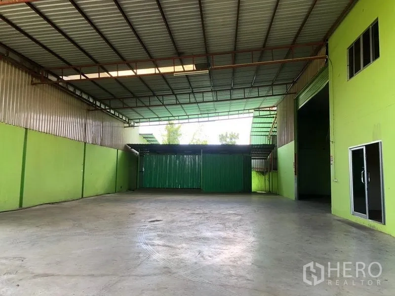 Factory for rent in Sam Khok, Pathum Thani - Spacious, high-ceiling warehouse interior with concrete floor and large roller doors.