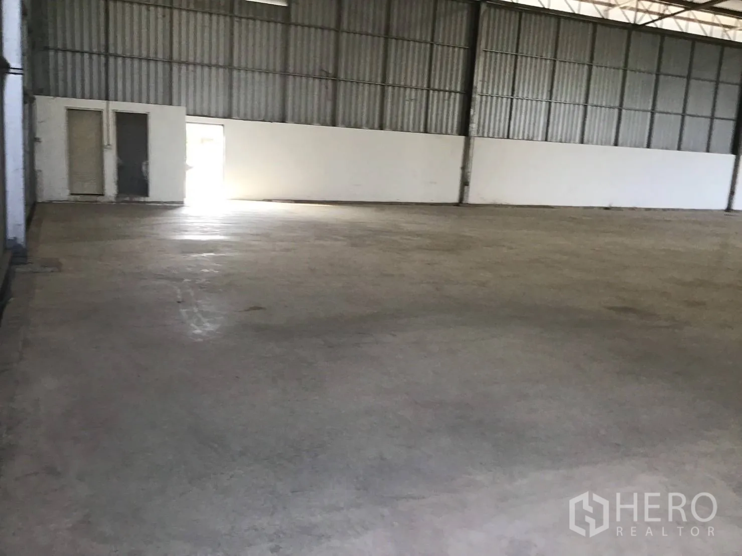 Warehouse for rent in Lat Krabang, Bangkok - Interior corner of warehouse with small office and restrooms beside an exit door.