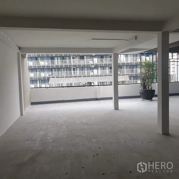 Home Office for rent in Khlong Toei, Bangkok - Covered semi-open workspace with wide balcony railing, potted plant, and city apartment views.