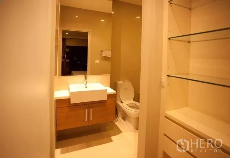Condominium for rent or sale in Watthana, Bangkok - Modern bathroom with floating vanity, square sink, mirror and glass shelving.