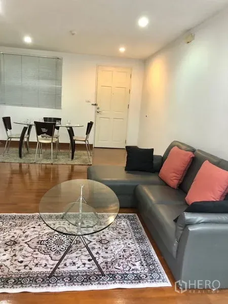 Condominium for rent or sale in Watthana, Bangkok - Cozy lounge facing the entry and dining set on warm wood flooring with recessed lighting.