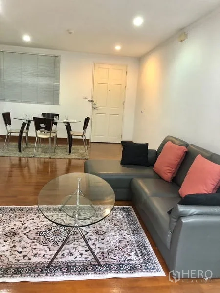 Condominium for rent or sale in Watthana, Bangkok - Cozy lounge facing the entry and dining set on warm wood flooring with recessed lighting.