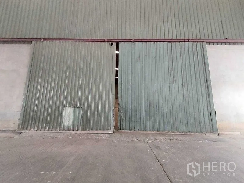Warehouse for rent in Lat Lum Kaeo, Pathum Thani - Close-up of large corrugated metal sliding warehouse doors at the loading area.