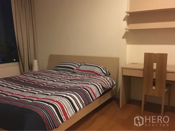 คอนโด ให้เช่าในWatthana, Bangkok - มุมห้องนอนอบอุ่น เตียงไม้ ชั้นวางของ และโต๊ะทำงานโทนสีอ่อน