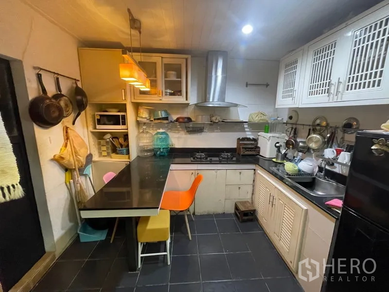 Home Office for sale - Compact kitchen with L-shaped counter, gas hob, range hood and pendant lights.
