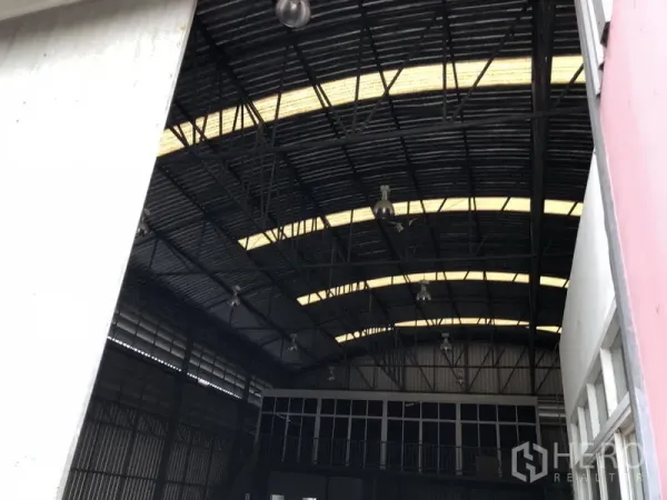 คลังสินค้า ให้เช่าหรือขายในLam Luk Ka, Pathum Thani - ภายในโกดังหลังคาทรงโค้งสูง มีแผ่นโปร่งแสงและโคมไฟอุตสาหกรรม พร้อมส่วนออฟฟิศชั้นลอยด้านหน้า