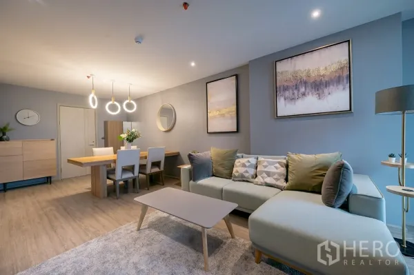 คอนโด ให้เช่าในKhlong Toei, Bangkok - มุมนั่งเล่นอบอุ่น โซฟาโทนพาสเทล ภาพแขวน และโต๊ะอาหาร