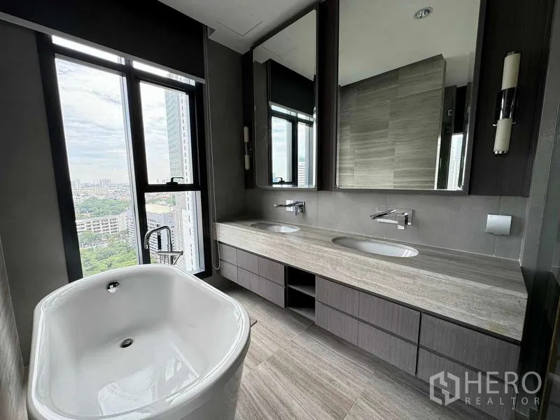 Condominium for sale in Bang Rak, Bangkok - Luxurious bathroom with freestanding bathtub, double vanity and city‑facing windows.