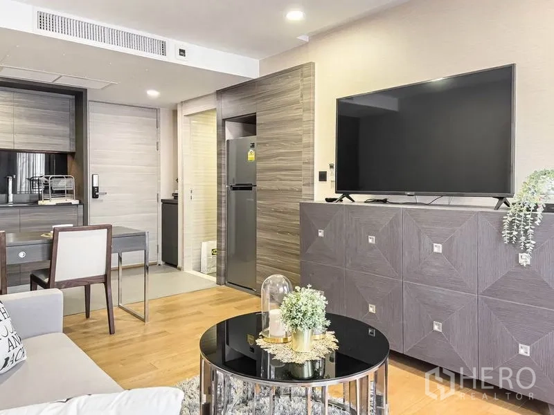 Condominium for rent in Pathum Wan, Bangkok - Open-plan living with large TV, kitchen, dining area, and stainless refrigerator.