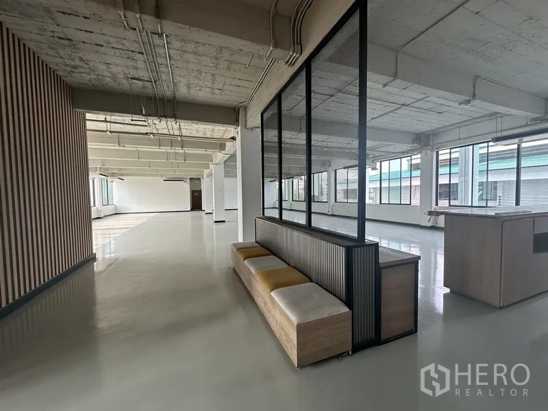 Office Space for rent - Open workspace featuring built-in bench divider and central island under exposed ceiling.