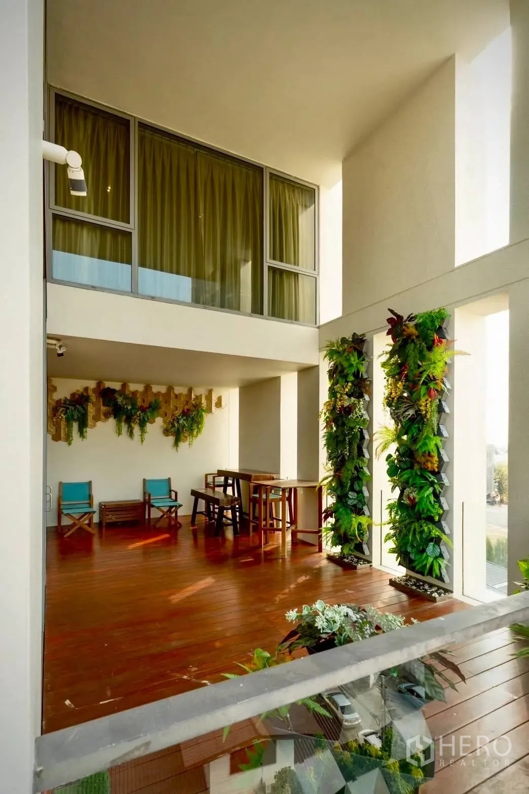 Condominium for sale in Sathon, Bangkok - Terrace area with wooden decking, tall windows, and vertical garden planters beside seating.