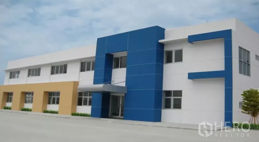 Factory for rent in Chachoengsao - Modern two-storey factory and office with blue-and-white facade, canopy entrance and wide paved yard in an industrial estate.