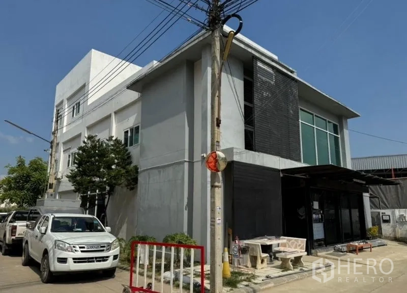Warehouse for rent or sale in Chon Buri - Multi-storey warehouse exterior with large glass facade, corner position and on-street parking.