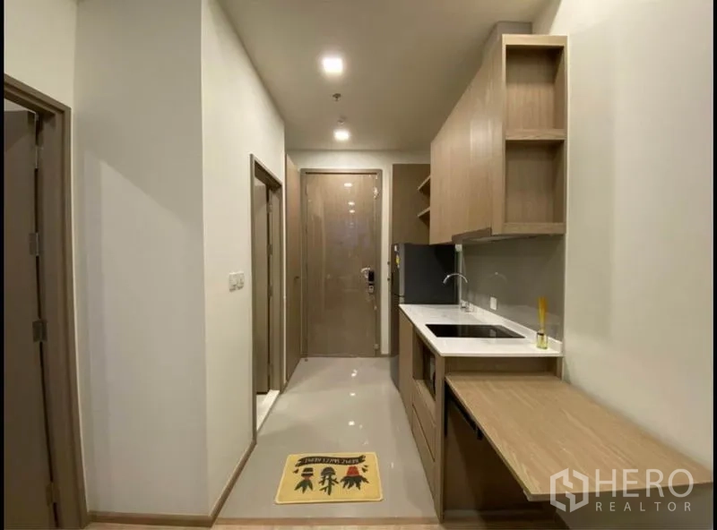 Condominium for sale in Chatuchak, Bangkok - Entry corridor kitchen with long countertop, sink and ample storage cabinetry.