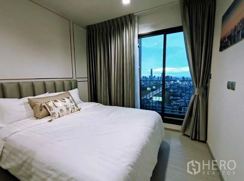 公寓 出租在Ratchathewi, Bangkok - 双人床卧室，推拉门通往阳台，远眺城市天际线。