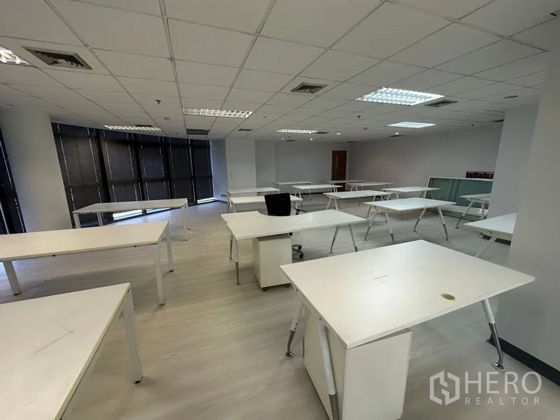 办公空间 出租 - 开放式办公室，白色工位、吊顶灯、浅色地板和大面积落地窗百叶。