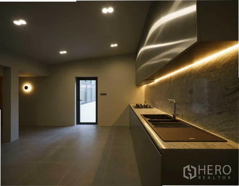 Home Office for sale in Wang Thonglang, Bangkok - Minimalist kitchen with long countertop, sink, gas hob and warm under-cabinet lighting.