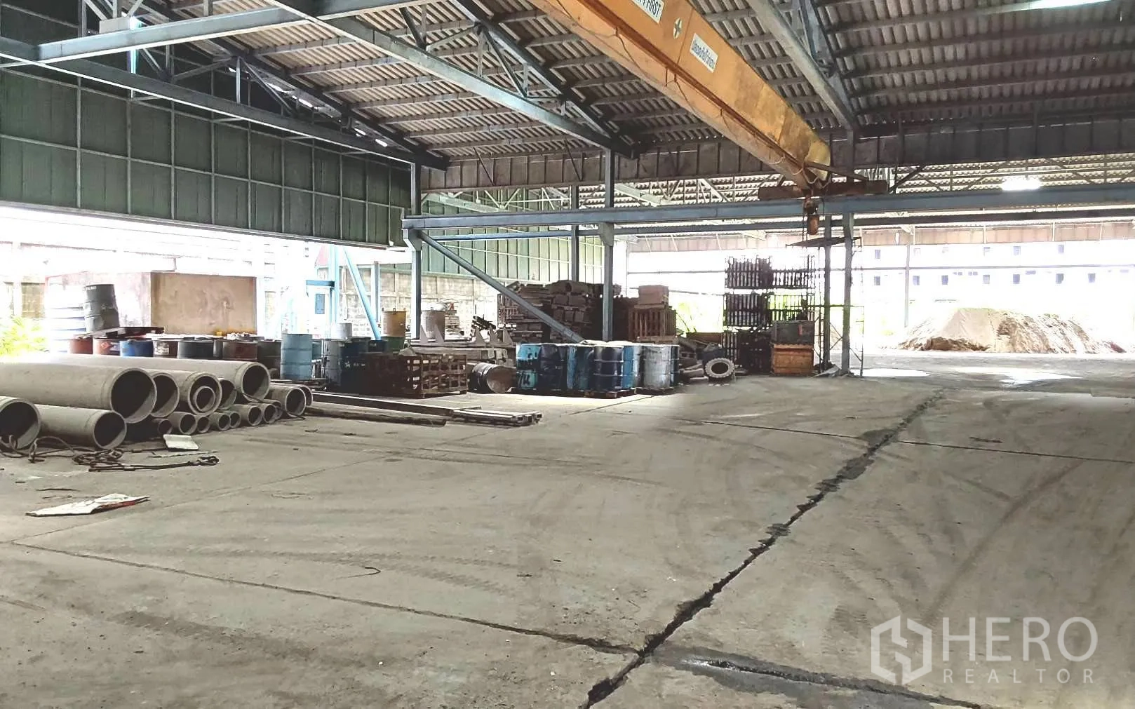 Factory for rent or sale in Bang Phli, Samut Prakan - Covered storage bay with stacked pipes, drums and materials.
