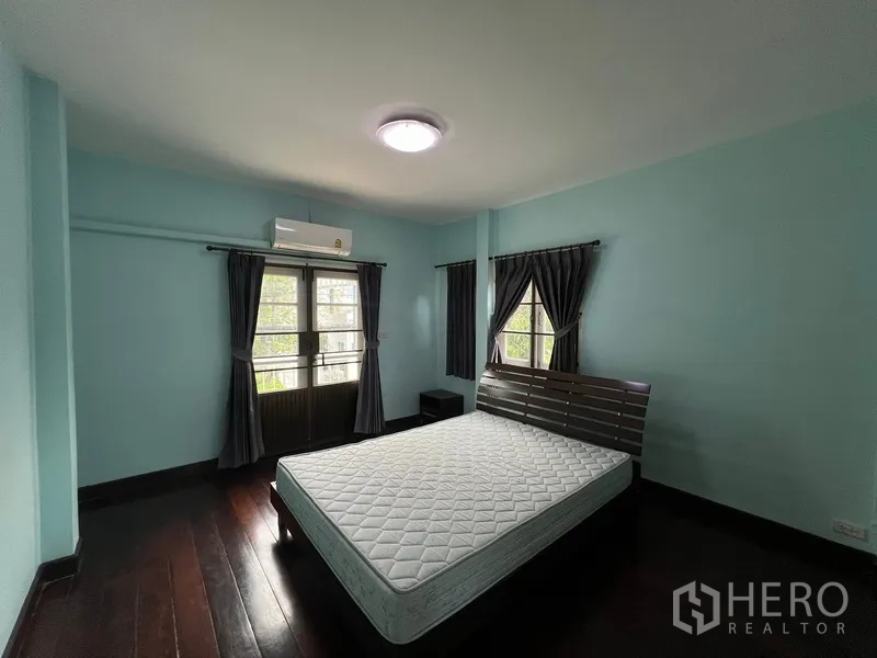 Detached House for rent in Bang Na, Bangkok - Master bedroom with dark curtains, balcony doors and wood floor