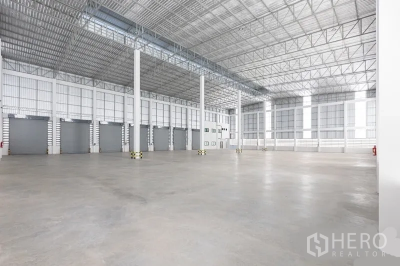 Warehouse for rent in Bang Bo, Samut Prakan - Wide warehouse floor with a row of roller-shutter loading docks and structural columns.