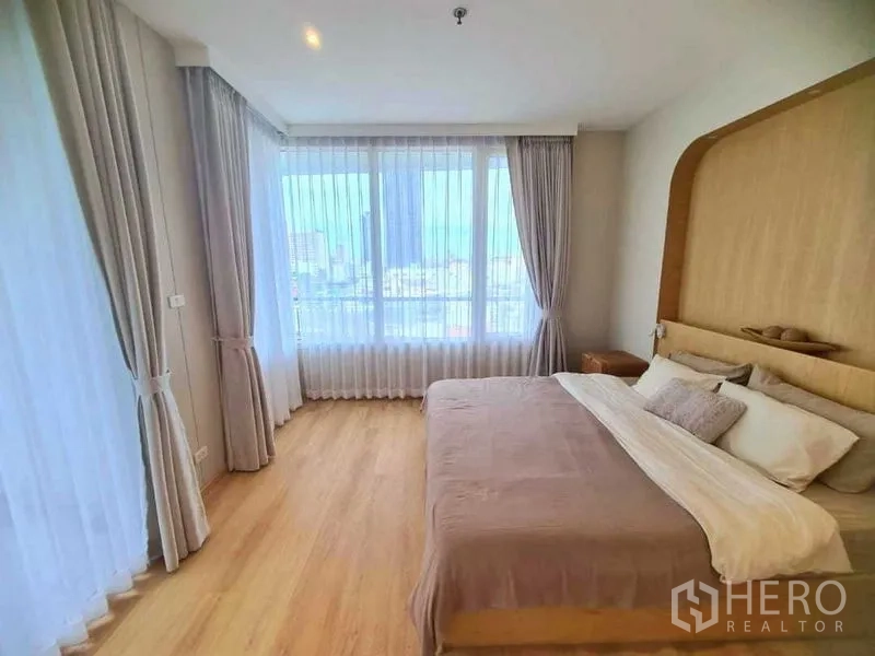 คอนโด ให้เช่าในRatchathewi, Bangkok - ห้องนอนมุมกระจก ม่านโปร่ง และวิวสกายไลน์กรุงเทพฯ