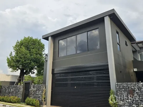 Detached House for sale in Thawi Watthana, Bangkok - Close view of the black roller garage door and upper floor windows of the house.
