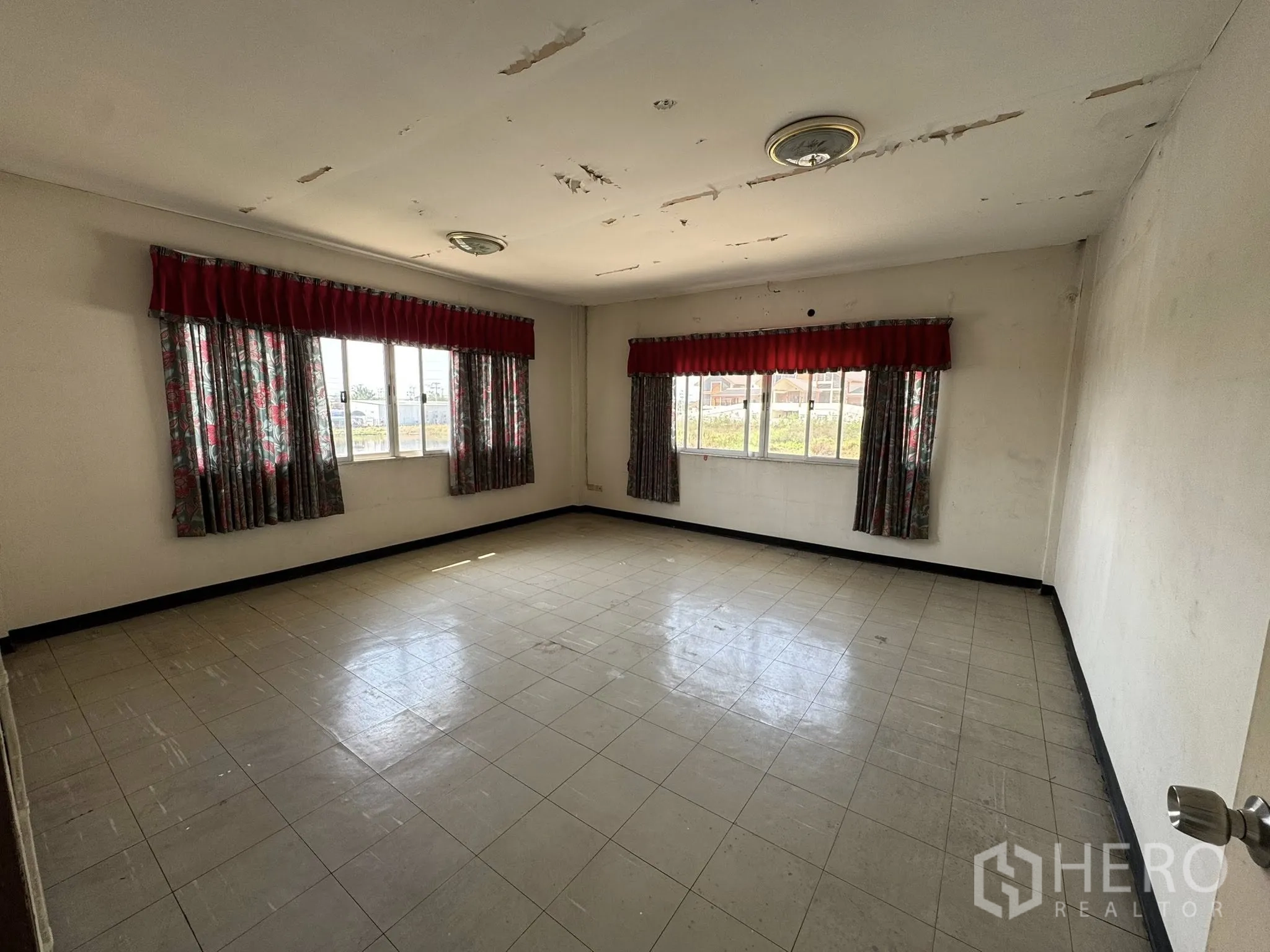货栈 for rent in Mueang Samut Sakhon, Samut Sakhon - 空置办公房，瓷砖地面，大窗配红色窗帘，天花有掉漆。