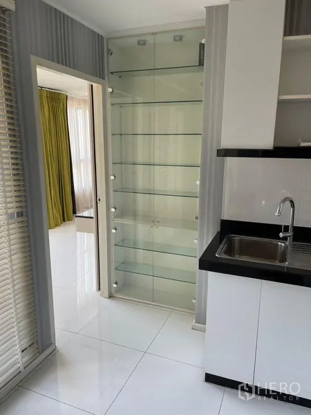 Condominium for sale in Suan Luang, Bangkok - Glass display shelves next to the kitchen sink with black countertop and white tiles.