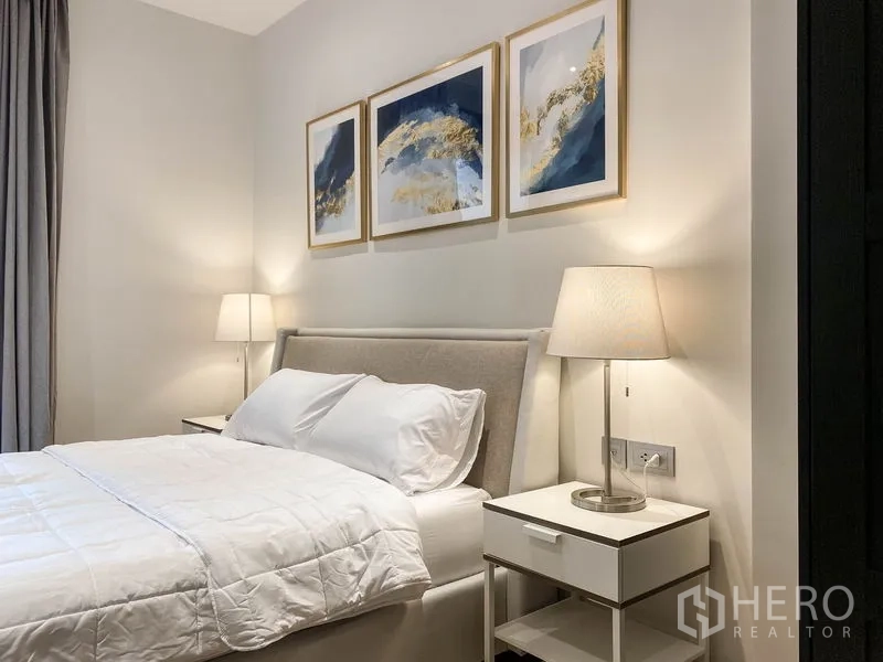 คอนโด ให้เช่าในDin Daeng, Bangkok - ห้องนอนบรรยากาศสงบ เตียงบุผ้า โคมไฟหัวเตียง และภาพศิลปะแบบนามธรรม