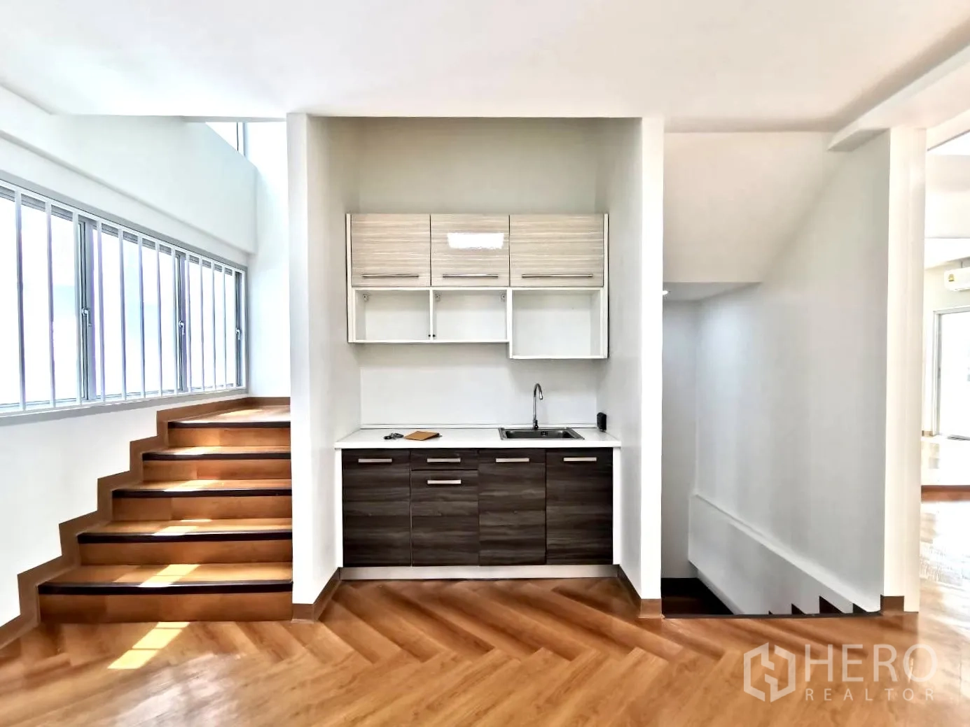 Home Office for rent in Watthana, Bangkok - Compact kitchenette by the staircase with long windows and wooden steps.