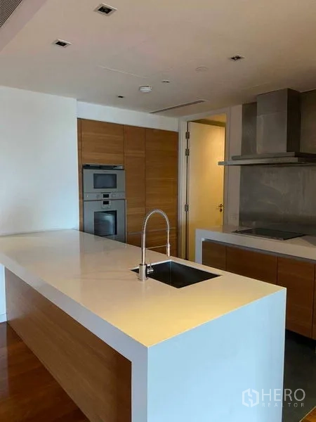 Condominium for rent in Yan Nawa, Bangkok - Open kitchen with white island sink, built-in oven and stainless range hood.