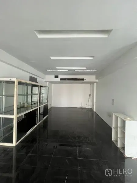 零售空间 出租在Watthana, Bangkok - 开放式室内空间，黑色亮面地砖、白墙与嵌入式照明。