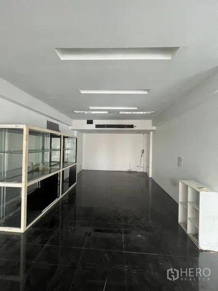 零售空间 出租在Watthana, Bangkok - 开放式室内空间，黑色亮面地砖、白墙与嵌入式照明。