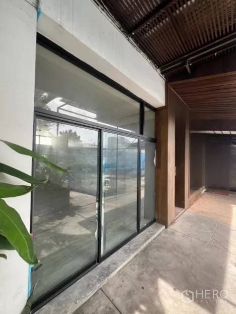 พื้นที่ขายปลีก ให้เช่า - หน้าร้านกระจกบานเลื่อนขนาดใหญ่ติดถนน พร้อมทางเดินมีหลังคาและต้นไม้ประดับ