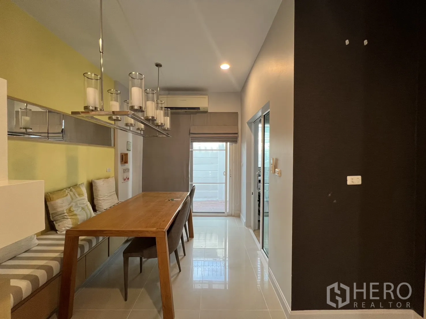 Townhouse for rent in Wang Thonglang, Bangkok - Dining corner with long wooden table, bench seating and pendant lights.