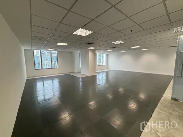 สำนักงาน ให้เช่าในWatthana, Bangkok - ภาพมุมกว้างของพื้นที่สำนักงานโล่ง มีเสาค้ำ พื้นกระเบื้องเงา และหน้าต่างหลายบานรับแสงธรรมชาติ