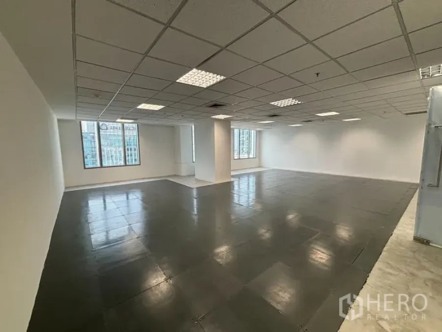 สำนักงาน ให้เช่าในWatthana, Bangkok - ภาพมุมกว้างของพื้นที่สำนักงานโล่ง มีเสาค้ำ พื้นกระเบื้องเงา และหน้าต่างหลายบานรับแสงธรรมชาติ