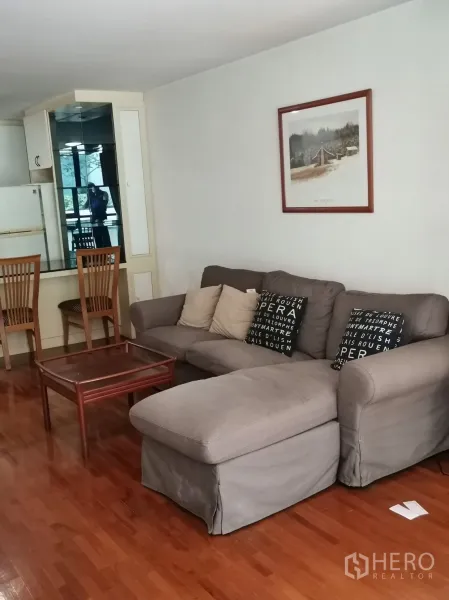 คอนโด ให้เช่าในPathum Wan, Bangkok - ห้องนั่งเล่นแบบโอเพนพร้อมโซฟาตัวแอลสีเทา โต๊ะกลาง และพื้นไม้เงา ข้างตู้กระจกบานใหญ่