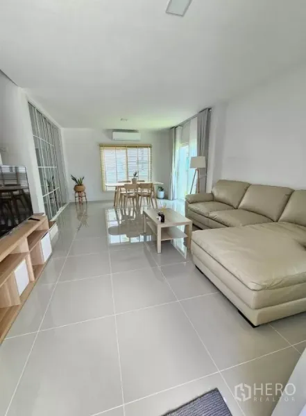 Detached House for rent in Bang Phli, Samut Prakan - Open-plan living and dining area with sectional sofa, glossy tile floors and large windows.