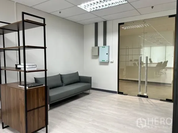 Office Space for rent in Sathon, Bangkok - Entry lounge with gray sofa and glass double doors leading to the main work area.