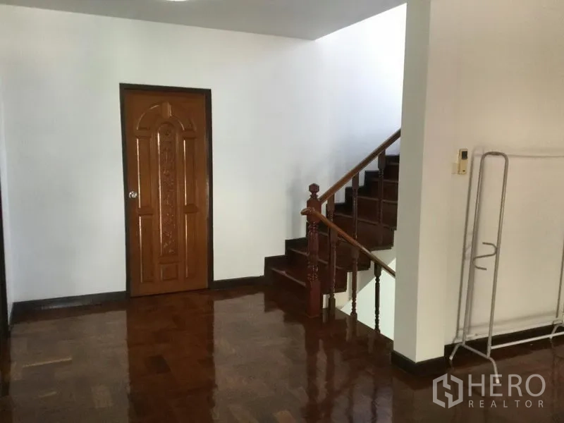 บ้าน ให้เช่าหรือขายในHuai Khwang, Bangkok - โถงบันได ประตูไม้แกะสลัก และบันไดไม้เงางามพร้อมราวจับ