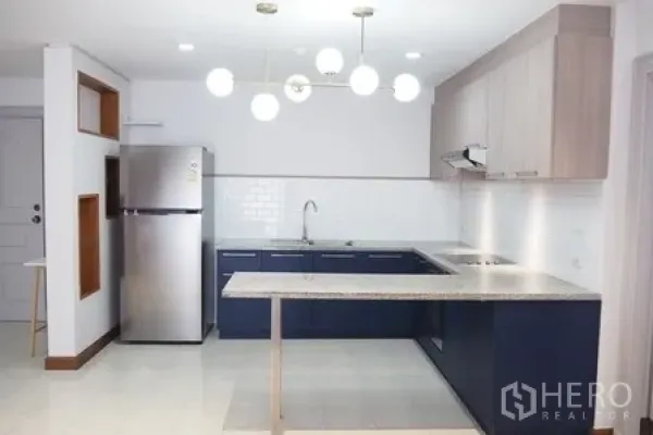 Condominium for rent in Pathum Wan, Bangkok - Modern L-shaped kitchen with pendant lights, fridge and white subway tile backsplash.