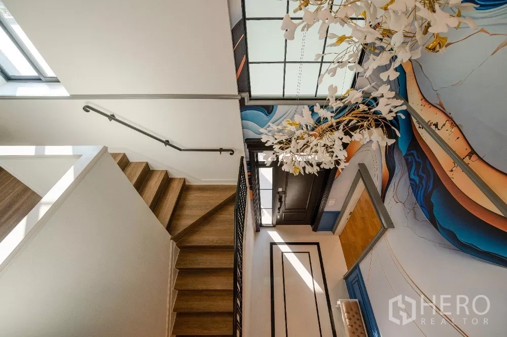 Detached House for rent or sale in Khlong Toei, Bangkok - Staircase with wooden steps and an artistic mural under a skylight at the entry hall.